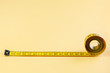 Yellow measuring tape on yellow background. Measuring tape for fitness. Close up