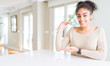 © Krakenimages.com - Beautiful young african american woman with afro hair sitting on table at home gesturing with hands showing big and large size sign, measure symbol. Smiling looking at the camera. Measuring concept.