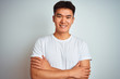 © Krakenimages.com - Young asian chinese man wearing t-shirt standing over isolated white background happy face smiling with crossed arms looking at the camera. Positive person.