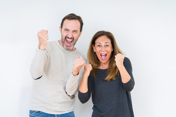 Poster - Beautiful middle age couple in love over isolated background very happy and excited doing winner gesture with arms raised, smiling and screaming for success. Celebration concept.