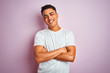 © Krakenimages.com - Young brazilian man wearing t-shirt standing over isolated pink background happy face smiling with crossed arms looking at the camera. Positive person.