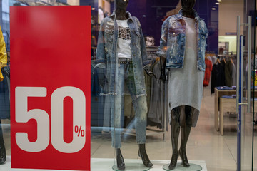 Season sale, black friday and shopping concept. Sale signs on stands in shop. Sale sign 50 percent discount price on stand in shop windows. Clothes on hangers and mannequins in the background.