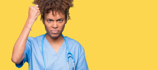 Young african american doctor woman over isolated background angry and mad raising fist frustrated and furious while shouting with anger. Rage and aggressive concept.