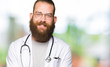 © Krakenimages.com - Young blond doctor man with beard wearing medical coat Smiling with hands palms together receiving or giving gesture. Hold and protection