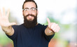 © Krakenimages.com - Young hipster man with long hair and beard wearing glasses showing and pointing up with fingers number six while smiling confident and happy.