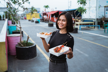 Wall Mural - young asian woman carrying korean street food at the rooftop cafe