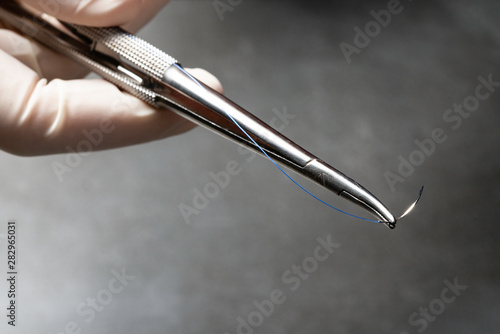 Doctor holding needle holder for surgery with blue nylon surgical thread Fototapete