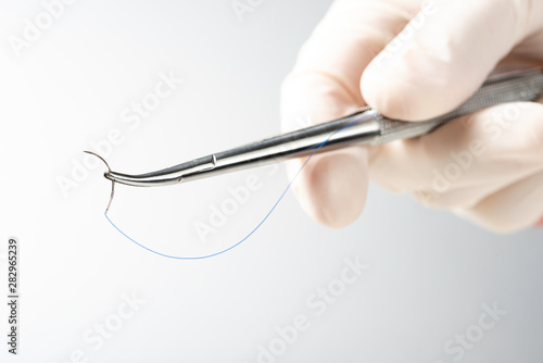 Cuadros en Lienzo Doctor holding needle holder on white background