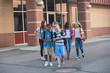 © Brocreative - Large, diverse group of kids leaving school at the end of the day. School friends walking together and talking together on their way home
