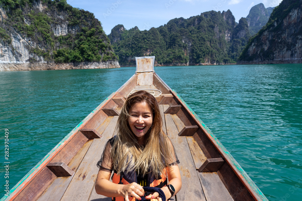Asian woman laughing on wooden boat with limestone mountains background - obrazy, fototapety, plakaty 