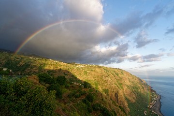 Wall Mural - Beautiful shot of a rainbow in a clear sky above hills