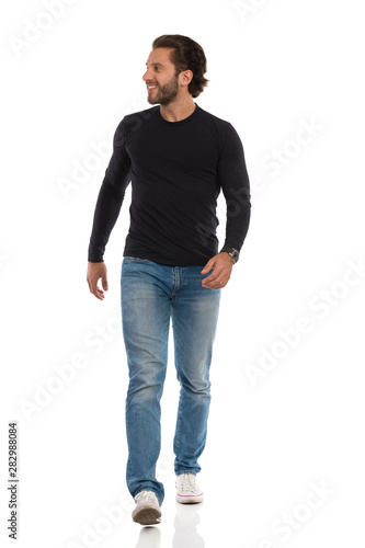 Smiling Man Black Jersey Jeans And Sneakers Is Walking Towards Camera And Looking Away Stock Photo Adobe Stock