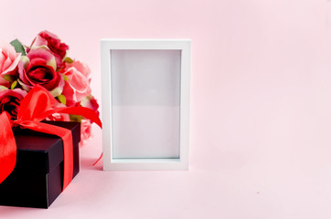 Wall Mural - gift box, roses and empty frame on a pink background