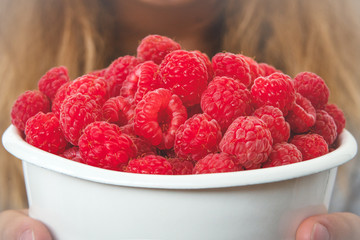 Wall Mural - girl holding a metal bucket with fresh ripe raspberries