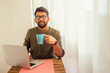© yurakrasil - Asian businessman freelancer working with a laptop and drinking coffee from blue cup at veranda balcony.freelance and remote work