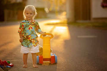 Poster - Beautiful toddler child, playing with plastic toys, blocks, cars on sunset