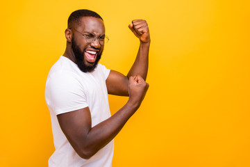 Dark skin guy celebrating lottery winning raising fist up wear casual outfit isolated yellow background