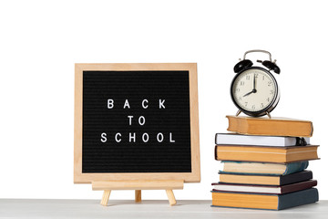 Back to school words on a letter board with books and vintage alarm clock against white isolated background