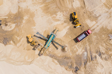 Aerial view of sand quarry with trucks and bulldozers. Heavy bulldozer loading  sand,