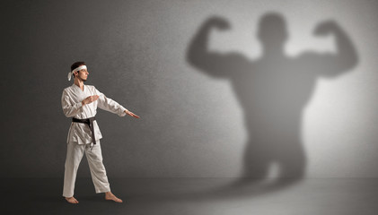 Wall Mural - Young karate man fighting with a big black scary shadow