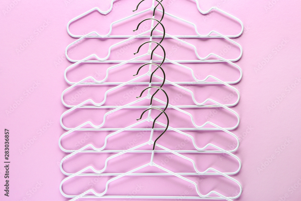 Many clothes hangers on color background