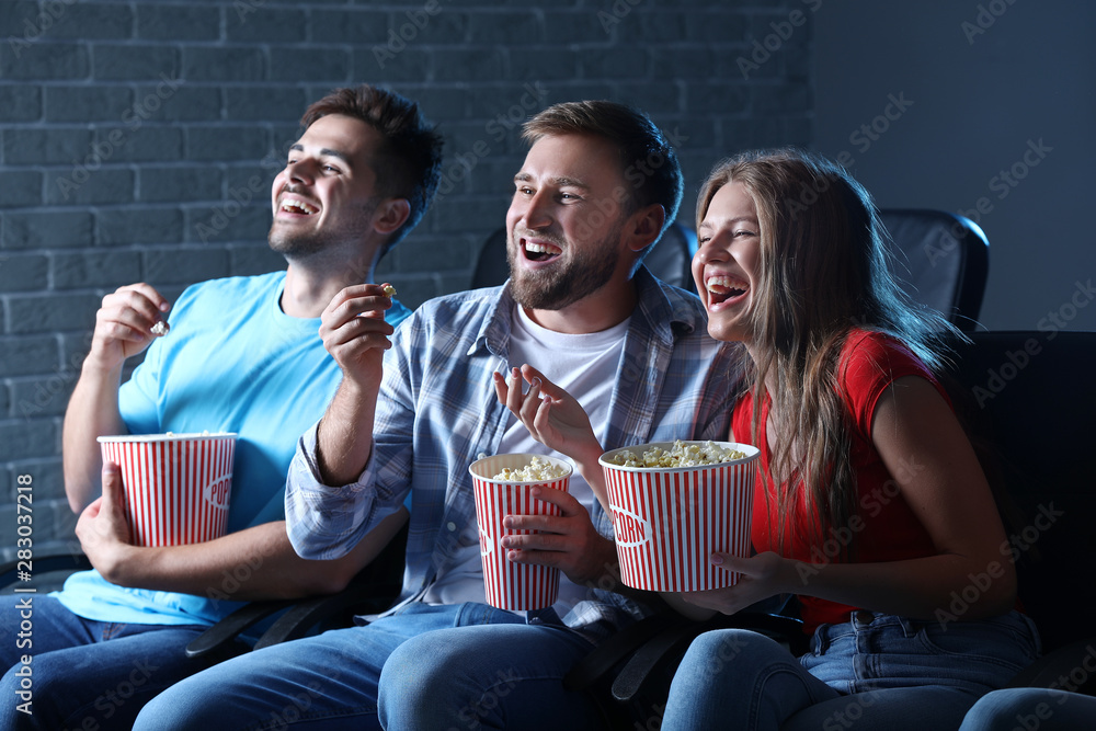 Friends with popcorn watching movie in cinema