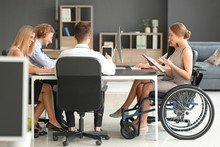 Handicapped Young Woman With Colleagues Working In Office