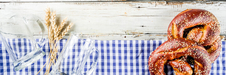 Wall Mural - Oktoberfest festive background with traditional Bavarian checkered tablecloth, pretzels and beer mugs.