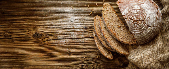 Bread,  traditional spelled sourdough bread cut into slices on a rustic wooden background, close-up, top view, copy space. Concept of traditional leavened bread baking methods