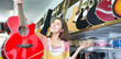© caftor - Brunette girl choosing acoustic guitar
