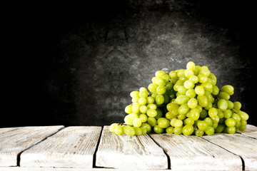 Wooden table background with green bunches of grapes