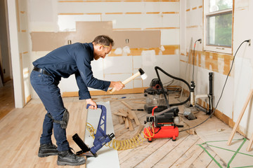 Wall Mural - A Male Worker install wood floor on a house