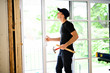 © Louis-Paul Photo - A handsome young man installing Double Sliding Patio Door in a new house construction site