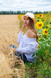 © Andrey_Arkusha - Brunette woman in white blouse sitting on a background of golden wheat and sunflowers fields