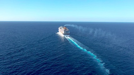 Wall Mural - Cruise ship liner goes into horizon the blue sea leaving a plume on the surface of the water seascape. Aerial view, concept of sea travel, cruises