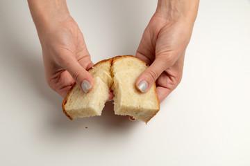 female hands are giving the two pieces of the white bread on the white background/table. internation