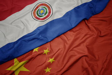 waving colorful flag of china and national flag of paraguay.