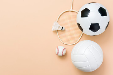 Wall Mural - Assorted sports equipment including a basketball, soccer ball, volleyball, baseball, badminton racket on a light brown background