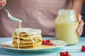 a girl in a pink apron adds condensed milk to pancakes. delicious healthy food. delicious pancakes w