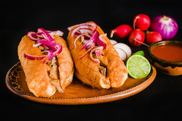 tortas ahogadas, traditional Mexican Food from Jalisco Guadalajara Mexico, spicy sandwich in a red sauce on a black background