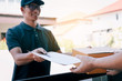 © wutzkoh - Young asian man smiling while delivering a cardboard box to the woman holding document to signing signature.
