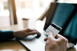 © wutzkoh - Close up hands of man are holding credit cards and using laptops computers are entering websites to buy products.