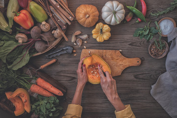 Wall Mural - Woman hands cutting vegetables on wooden background. Vegetables cooking ingredients, top view, copy space, flat lay.