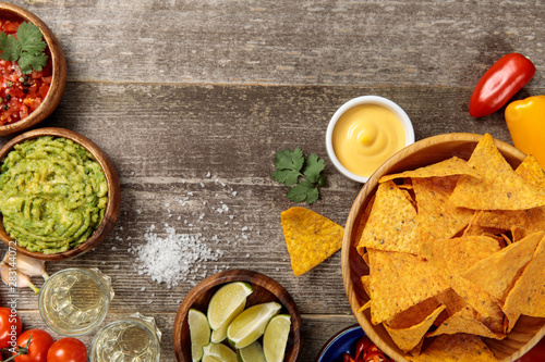 Fotografía top view of Mexican nachos served with cheese sauce, guacamole and salsa on weat