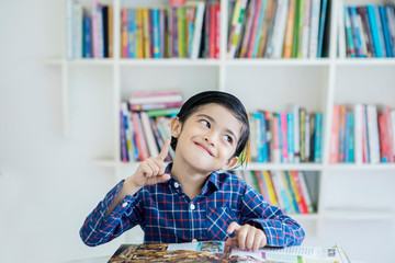 Happy little boy thinking an idea in the library