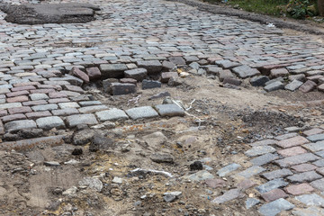 Sticker - Damaged asphalt road with potholes, caused by freeze-thaw cycles in winter. Bad road. Broken pavements sidewalks on sidewalk. pavement with paving slabs with defects and cracks coming in perspective