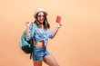 © Smeilov - The girl tourist with backpack on a yellow background shows the passport