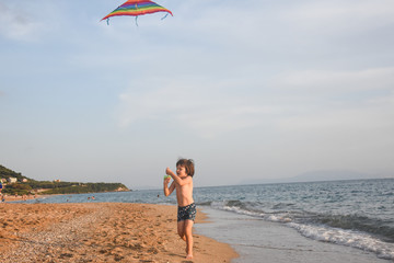 Little boy playing with kite on tropical beach. Summer vacation concept, child playing on sandy beach