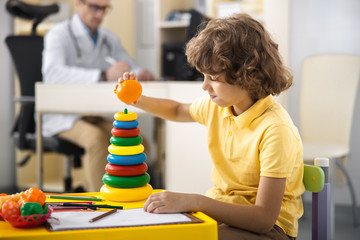 Curly boy playing with pyramid in clinic stock photo