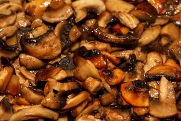 Poster - Fried champignon mushrooms in a pan closeup background texture